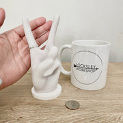 Size comparison for peace sign ring holder. Includes a hand, mug, and quarter.