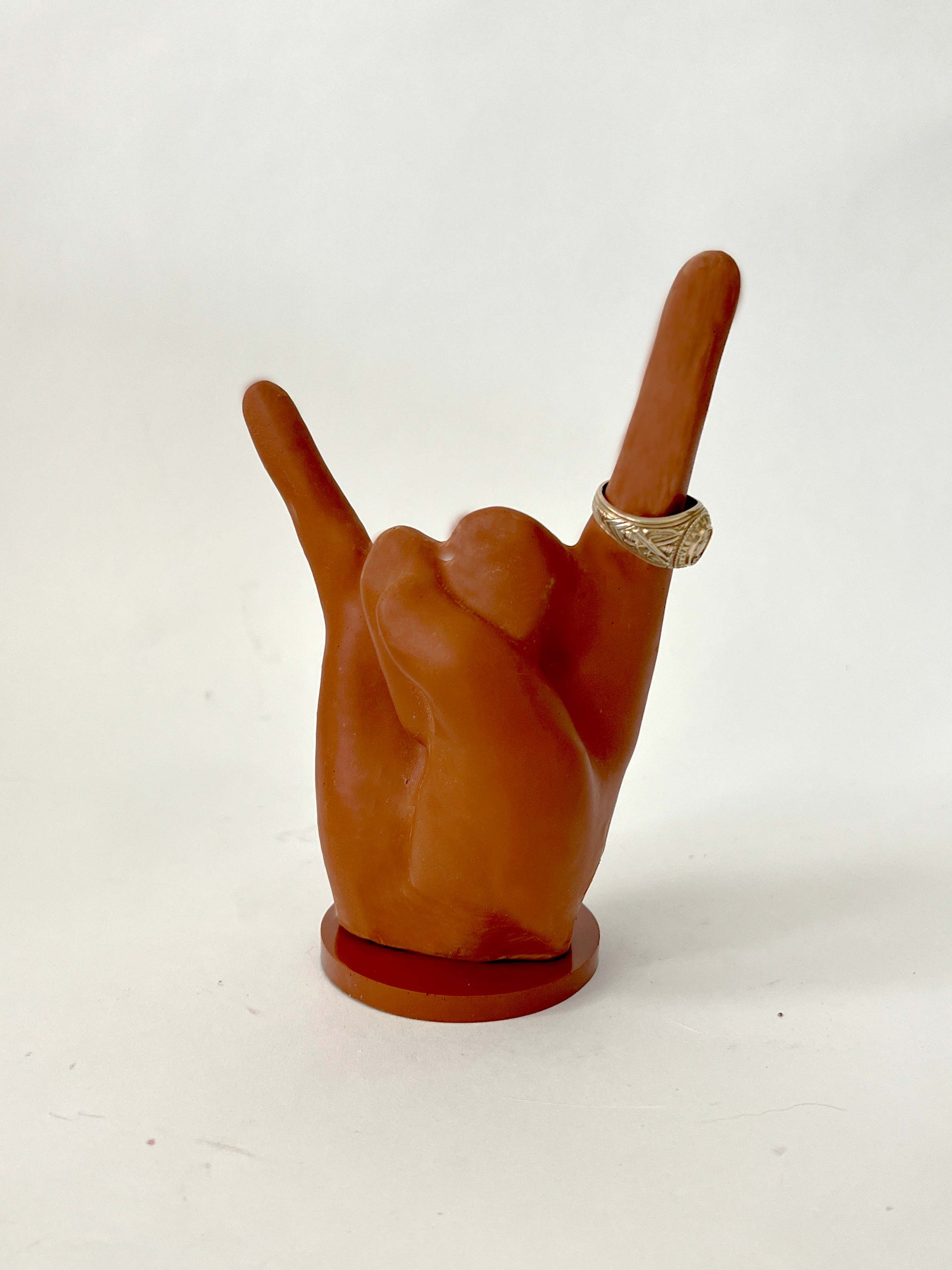 burnt orange ring holder signaling hook 'em horns. Ring holder is situated on a burnt orange base.