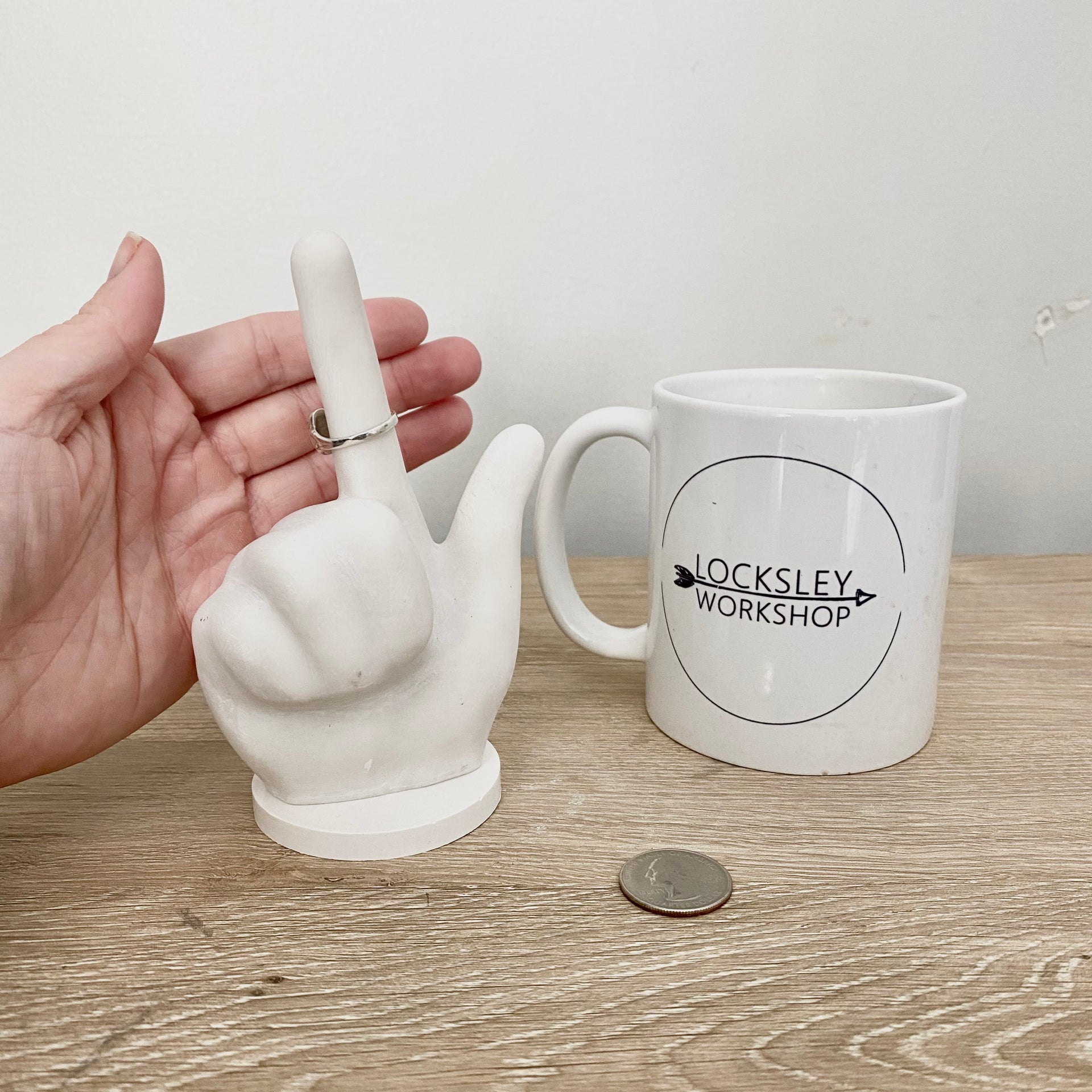 Mug, Quarter and hand with the ring holder for size comparison on a desk