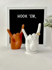 one burnt orange and one white bonded marble ring holders signaling hook 'em horns.