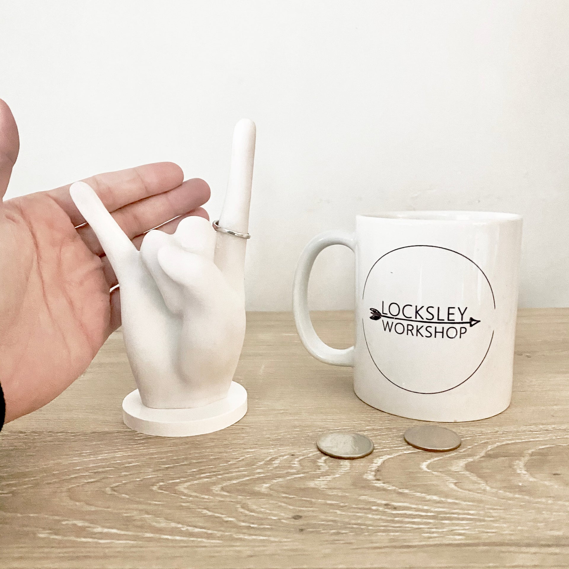 size comparison image for the ring holder. includes a hand, mug, and quarter for reference.