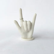 White bonded marble ring holder signaling I Love You in ASL.